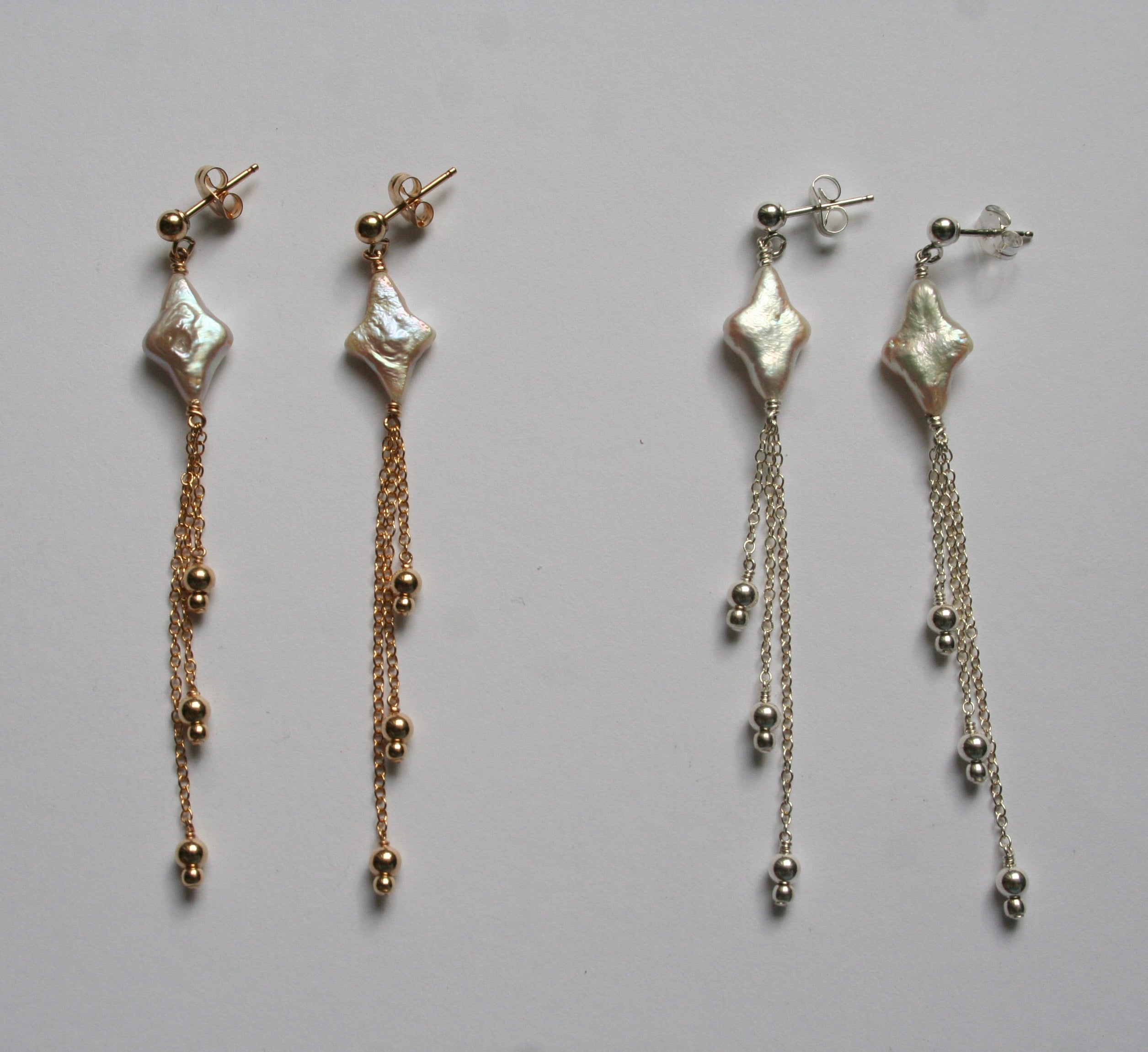 Pair of gold and silver earrings on a gray background