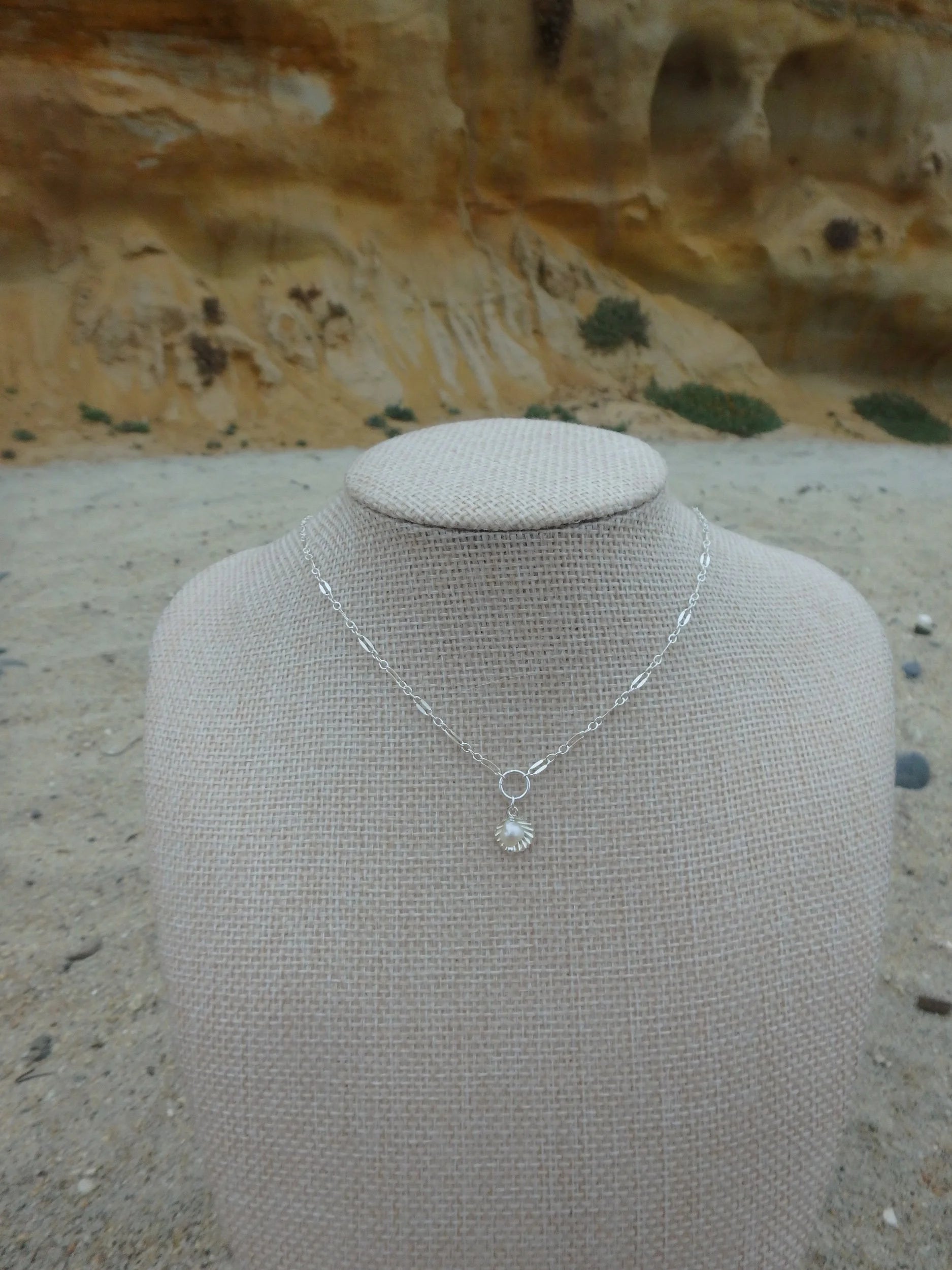 Silver necklace with a pendant on a mannequin bust against a natural background